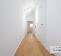 A hallway with a wooden decor floor in a family house, white walls and doors.