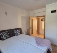 Bedroom in a family house with a double bed, nightstands, and a wooden-decor floor.