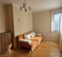 Living room with an orange sofa and wood-patterned flooring in a family house.