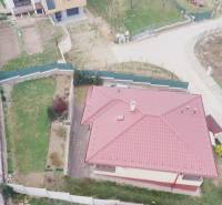 A family house in Ličartovce with a red roof, a garden, and a nearby access road.