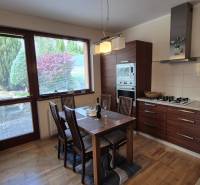 A kitchen in a family house with a wooden decor floor and a view of the garden.