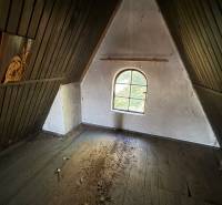 Attic room in a cottage with a window and a floor with wooden decor.