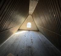 An attic room in a cabin with wooden walls and a wooden decor floor.