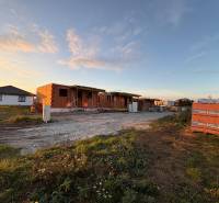 Construction of houses in Ľubotice during sunset, with visible brick walls.