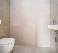 Toilet with a sink in a 4-room apartment, light tiles, minimalist design.