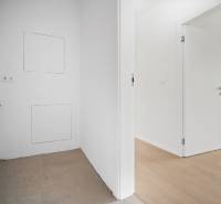 An empty room in a 4-room apartment with a wood-patterned floor and white walls.
