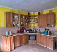 A kitchen in a family house with wooden decor on the furniture and yellow walls.