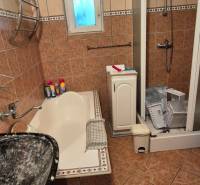 Bathroom in a family house with a bathtub, shower, and ceramic tiles.