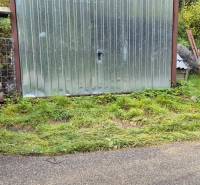 A metal garage by a family house on Škoruby Street in Kolárovce, surrounded by greenery.