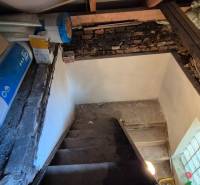 A basement in a family house with a staircase, a brick wall, and building materials.