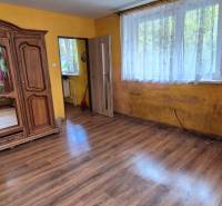A room in a family house with a rustic wardrobe, a large window, and a floor with a wooden decor.