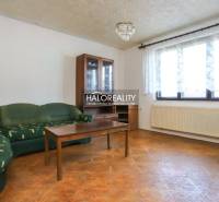 Living room in a family house with a corner sofa, coffee table, and glass display cabinet.