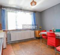 Kitchen with dining area in a family house, red chairs, gray walls, large window.