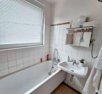 A bathroom with a classic bathtub, sink, and tiles in a 3-room apartment.