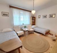 A bright room with curtains, two beds, an armchair, and a round carpet in a 3-room apartment.