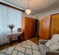 Living room in a three-room apartment with a light carpet and wooden decor on the furniture.