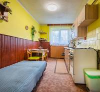 A kitchen with a dining table and a sofa in a 3-room apartment with yellow walls.