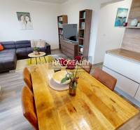 Living room in a 3-room apartment with a sofa, dining table, and wooden decor flooring.