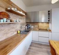 A kitchen in a 3-room apartment with wooden decor and shelves for dishes.