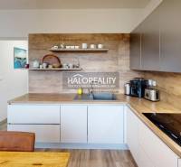 A kitchen in a 3-room apartment with light furniture and a wooden decor floor.