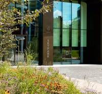 Entrance to the Sky Park building in Bratislava on Bottova, surrounded by trees and flowers.