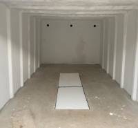 An empty garage with a rectangular opening on the floor, two walls in the Garage Trenčín on Legionárska.