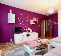 A colorful living room with white furniture, a glass table, and a wooden decor floor in a studio apartment.