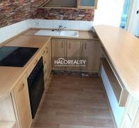 A kitchen in a 2-room apartment with a wooden decor floor and brick cladding.