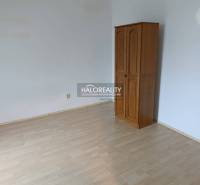 A room in a 2-room apartment with a wooden decor floor and a wardrobe.