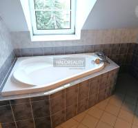 A bathroom in a 2-room apartment with a shower, sink, and light-colored tiles.