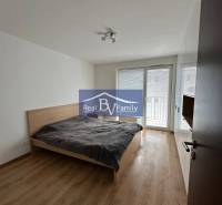 A bedroom with a bed, wooden decor flooring, and a built-in wardrobe in a 2-room apartment.