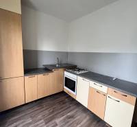 A kitchen in a 3-room apartment with a wooden decor floor and a gas stove.