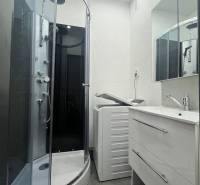 Bathroom in a 3-room apartment with a shower, washing machine, and sink with a mirror.