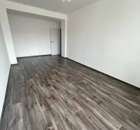 A spacious room with a wooden decor floor and white walls in a 3-room apartment.