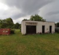 A garden with a building in Turčianske Teplice near a 3-room apartment, surrounded by trees and lawn.