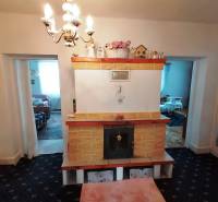 A fireplace in the living room of a three-room apartment with tile decorations and a pendant light.
