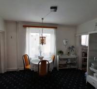 Dining area in a 3-room apartment with floral curtains and a glass cabinet.