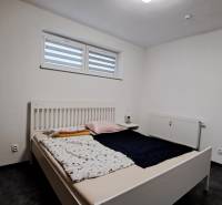 A bedroom with a gray floor in a 2-room apartment, a bed, and white walls.