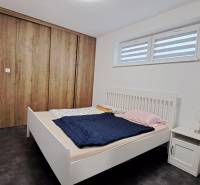 A bedroom with a white bed and a large wardrobe with a wooden decor in a 2-room apartment.