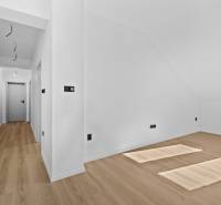 White wall in a 3-room apartment on Trnavská cesta street with a slanted window and wooden floor.
