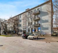 On Trnavská cesta street, you can see an apartment building with trees and a parked car.