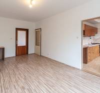 A room with a wooden decor floor and a kitchenette in a 3-room apartment.