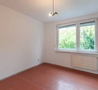 A room in a 3-room apartment with a window, white walls, and a floor with a wood decor.