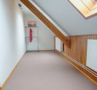 A hallway in the attic with wooden paneling, a radiator, and a coat rack in a family house.