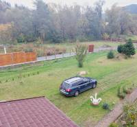 In Liptovská Porúbka, a family house with a lawn, a car, and the surrounding green landscape.