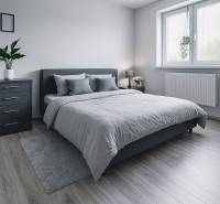 A bright bedroom in a family house with a comfortable bed and a wooden decor floor.