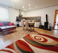 Living room in a family house with a kitchenette, sofa, and wooden decor flooring.