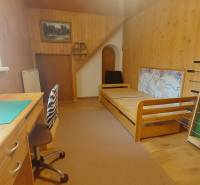Interior of a family house with wooden decor, furniture, bed, and work desk.