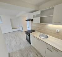 A kitchen with built-in cabinets and appliances in a 3-room apartment, flooring with a wood decor.