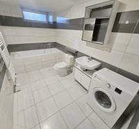 A bathroom in a 3-room apartment with a washing machine, bathtub, and tiles.